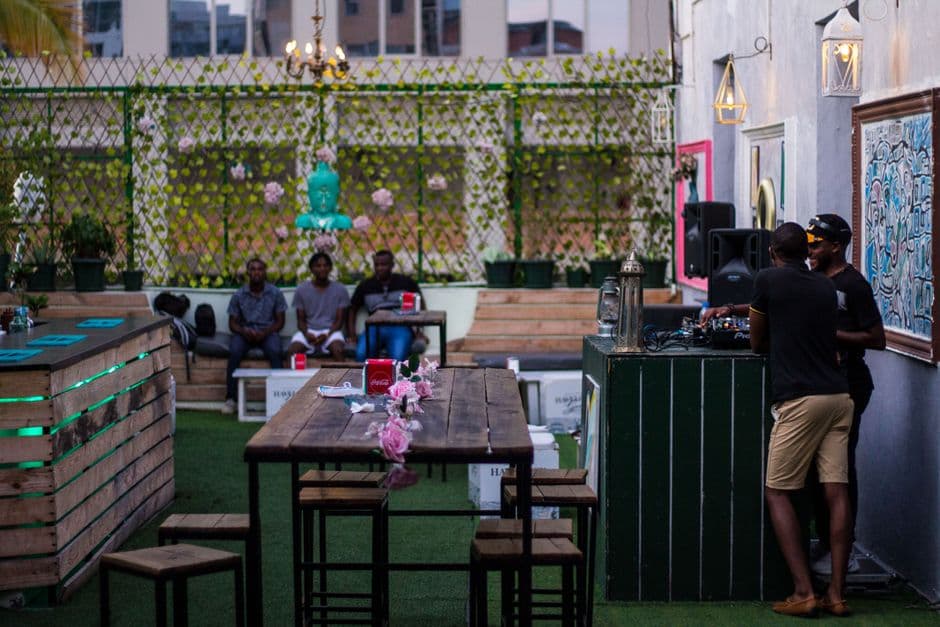 Terrasse animée d’un maquis en soirée, tables et boissons