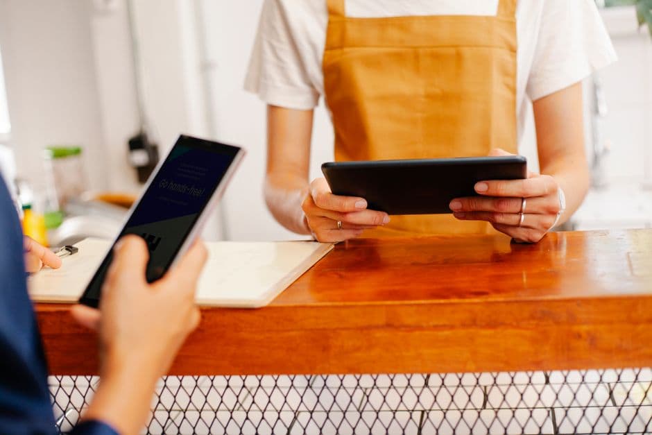Comerciante cobrando con una tablet en el mostrador de su tienda