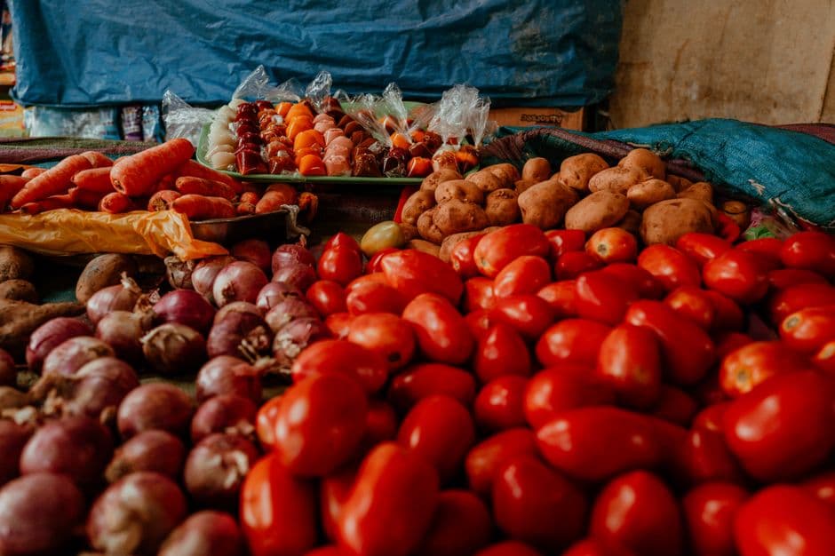 Outdoor market stall with fresh tomatoes, onions and potatoes