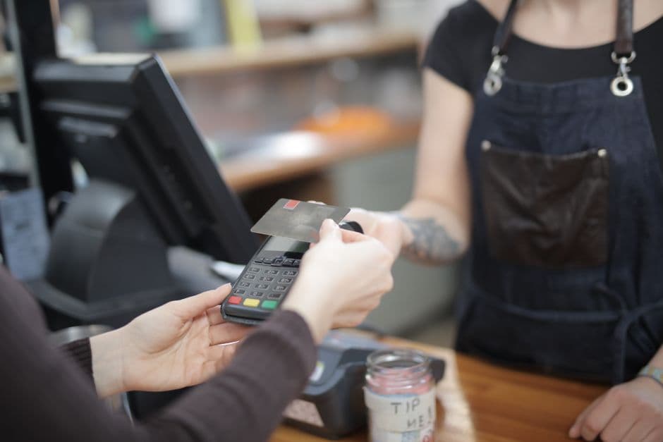 Cliente pagando con tarjeta en un lector sobre el mostrador de una tienda